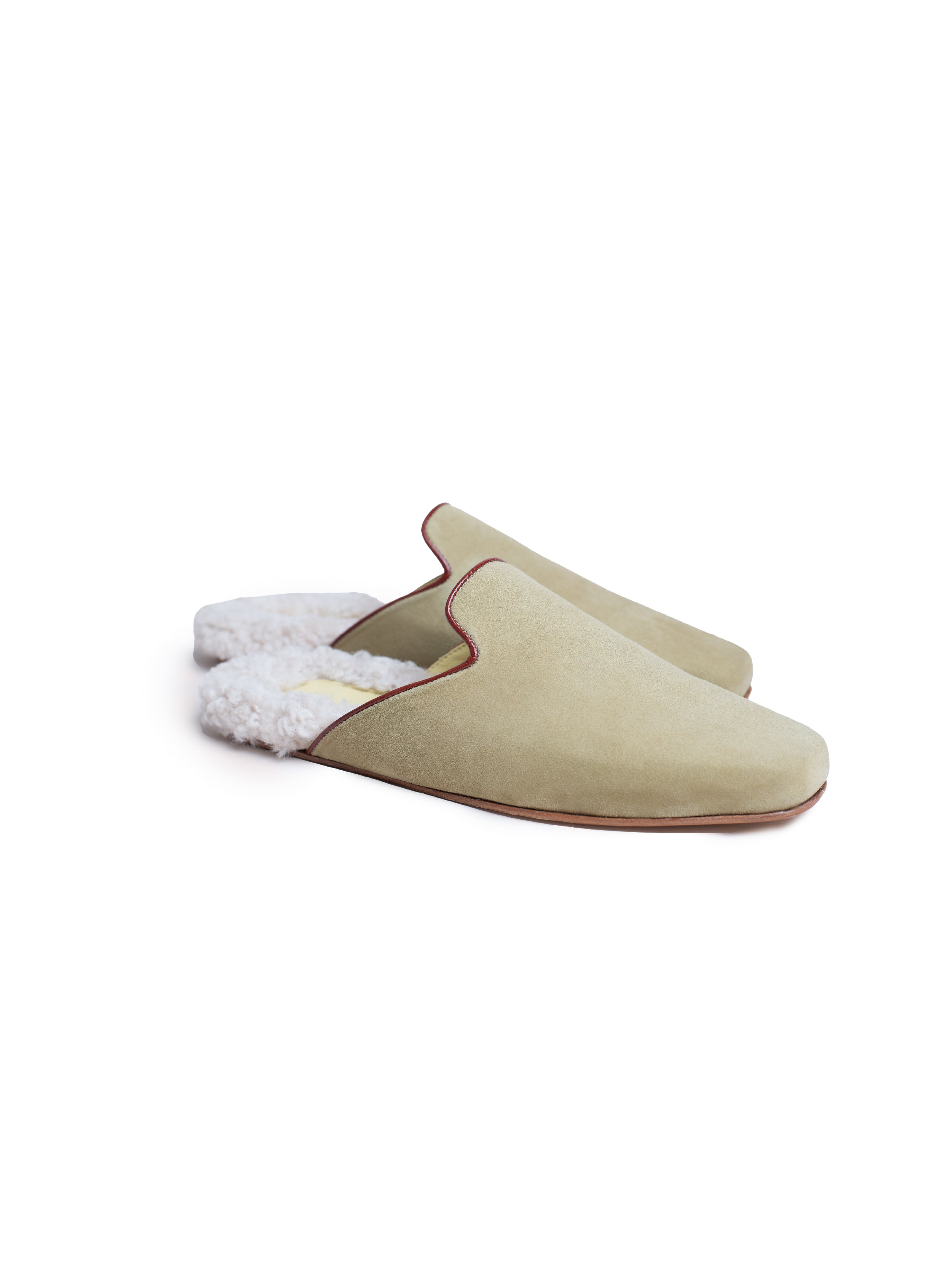 Pair of green suede slippers with white shearling lining on a white background