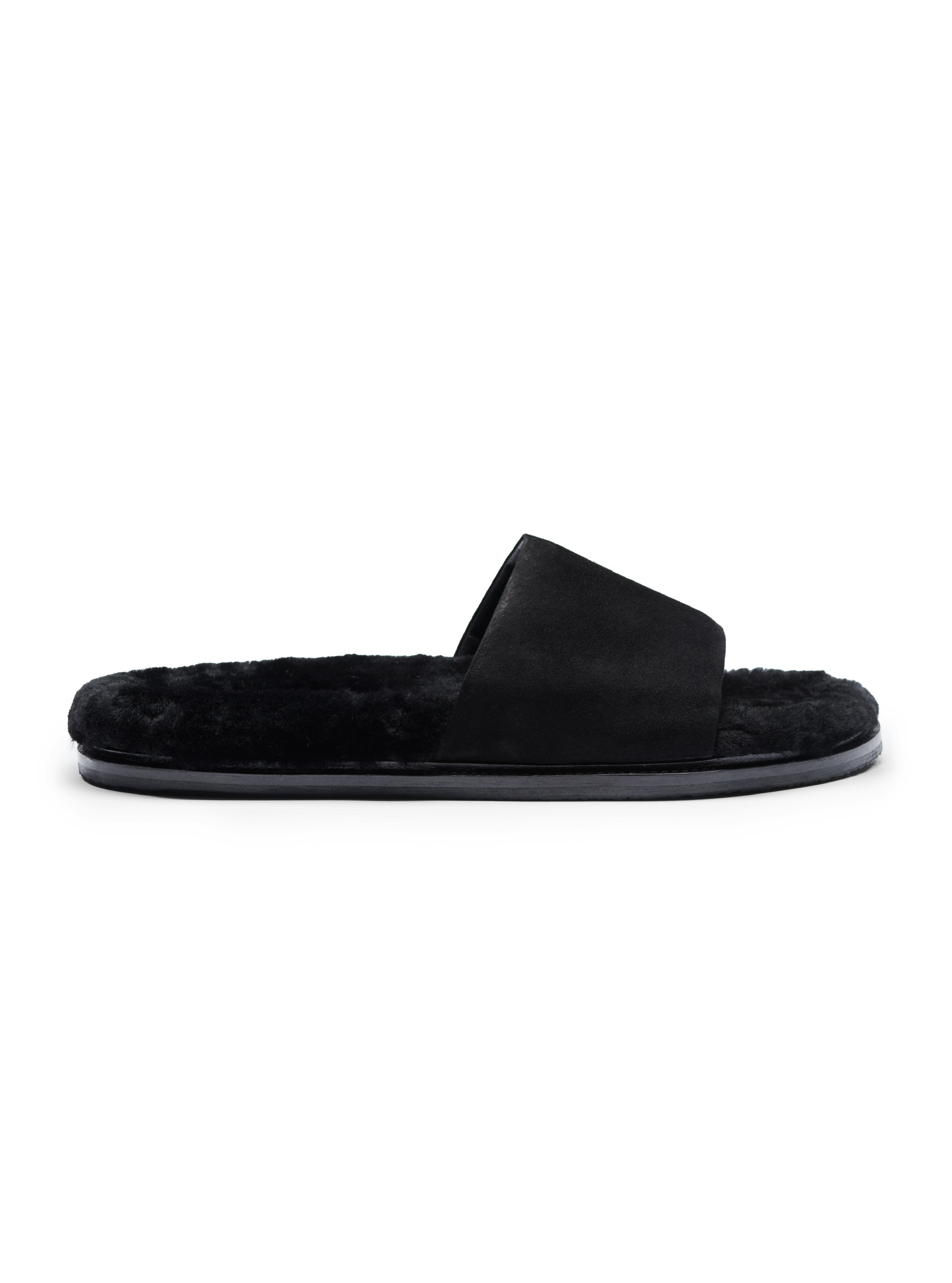 Men's pair of slip-in slippers with black fur lining, black suede, and rubber sole on a white background.