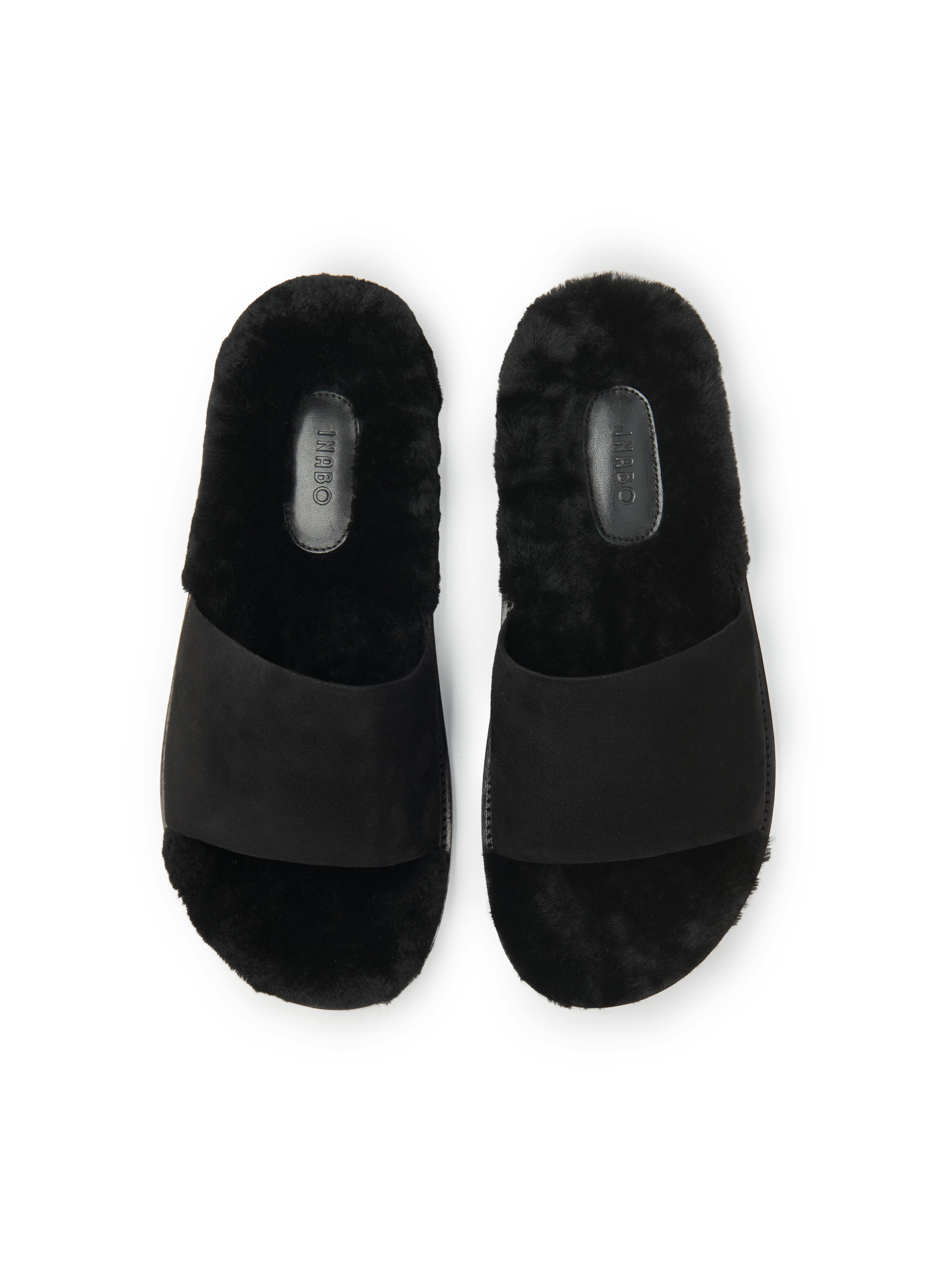 Men's pair of slip-in slippers with black fur lining, black suede, and rubber sole on a white background.