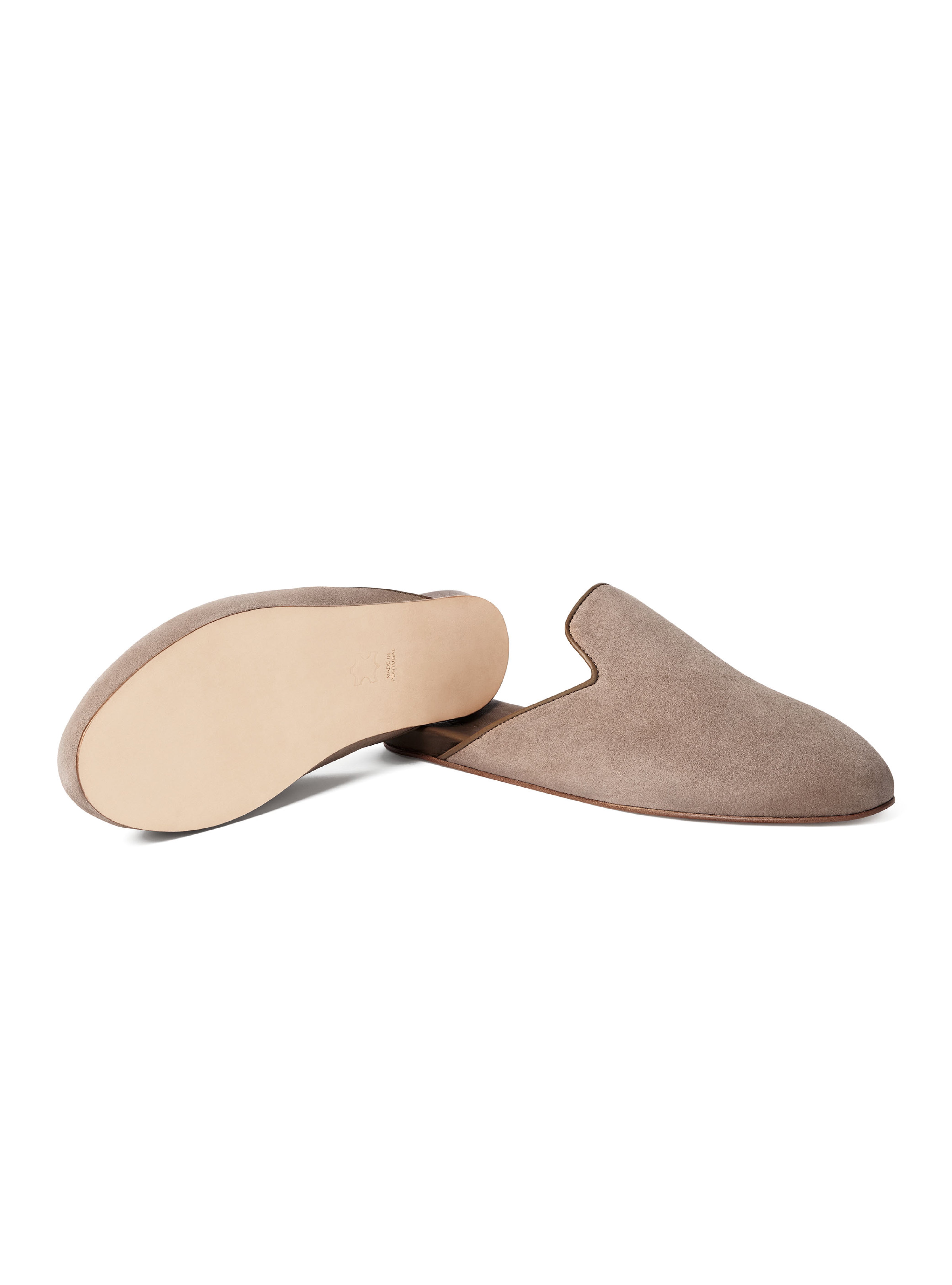 Pair of taupe suede slippers with leather outsole on a white background