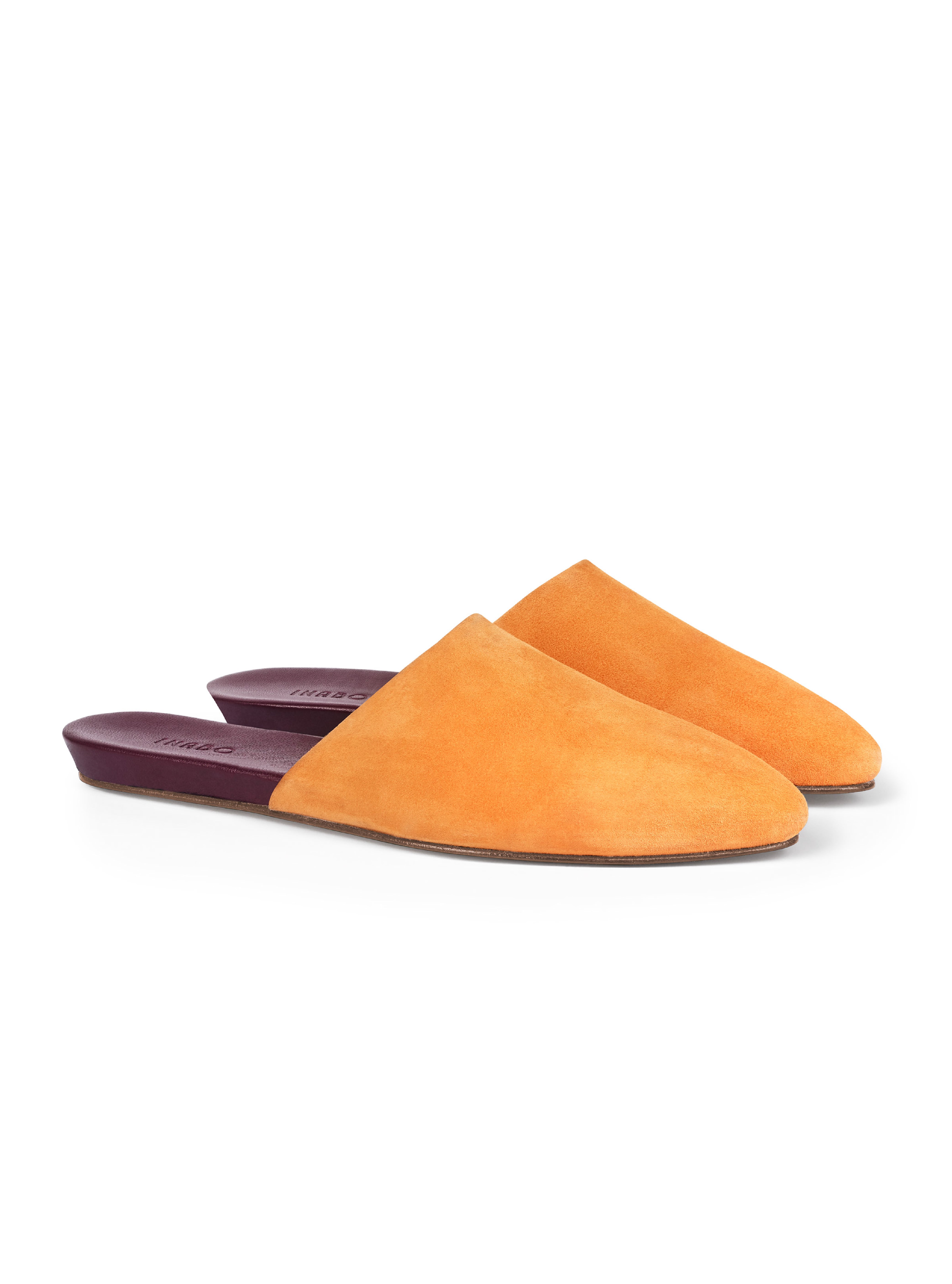 Women's pair of saffron yellow suede pointed-toe slippers with burgundy insoles on a white background