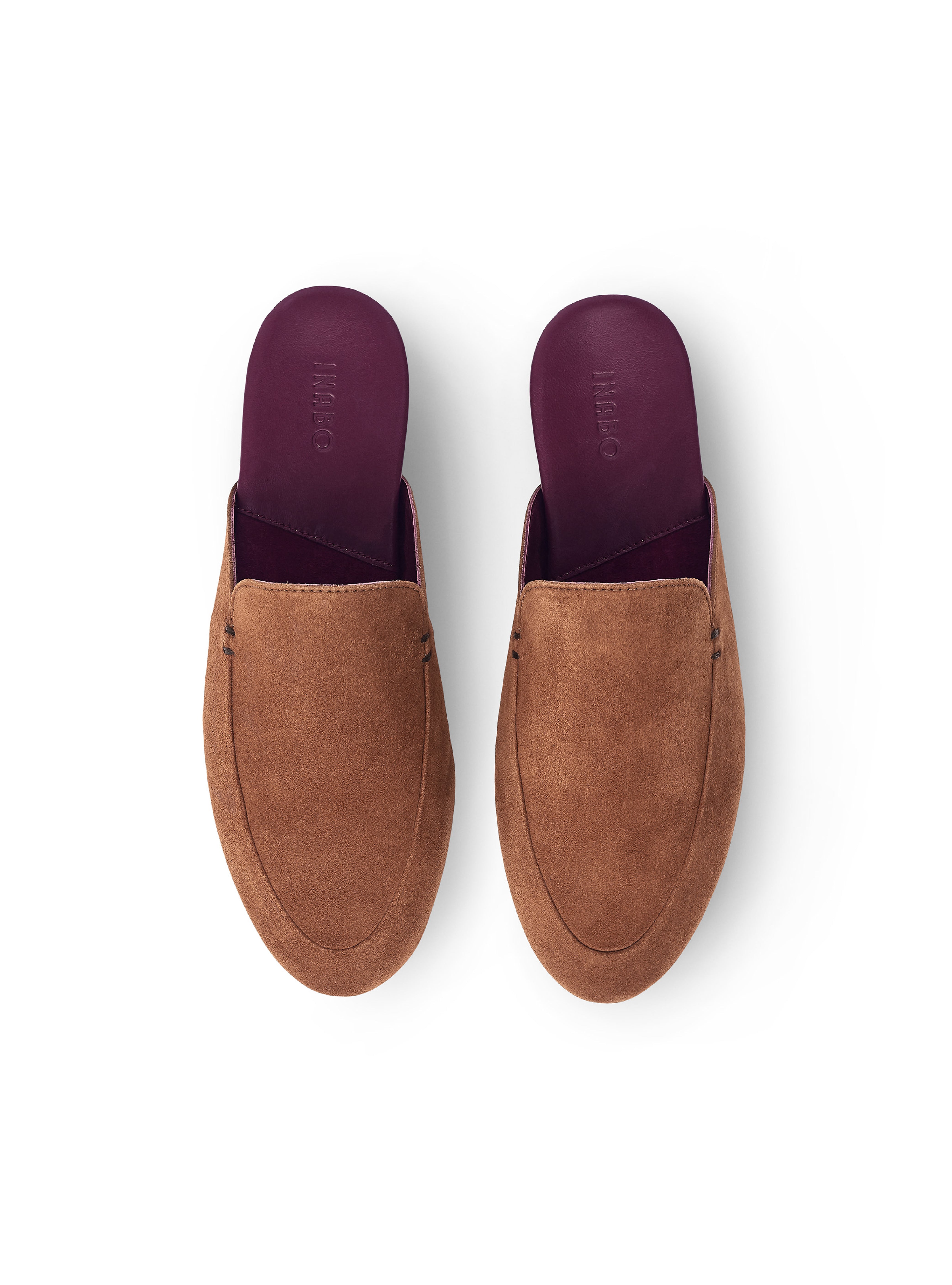 Women's pair of brown suede slippers with a burgundy insole on a white background.