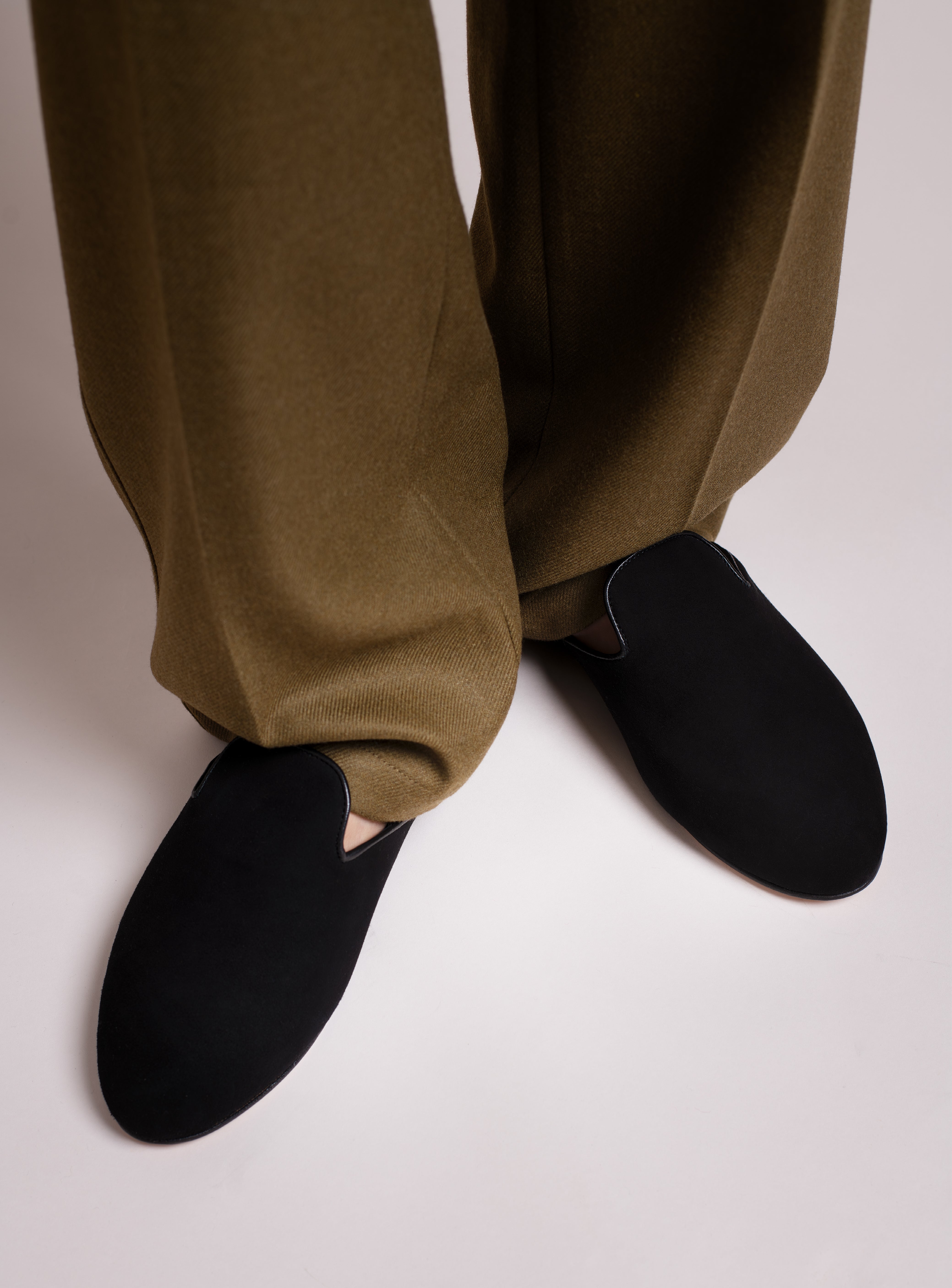 Man wearing khaki green pants with black suede slippers.