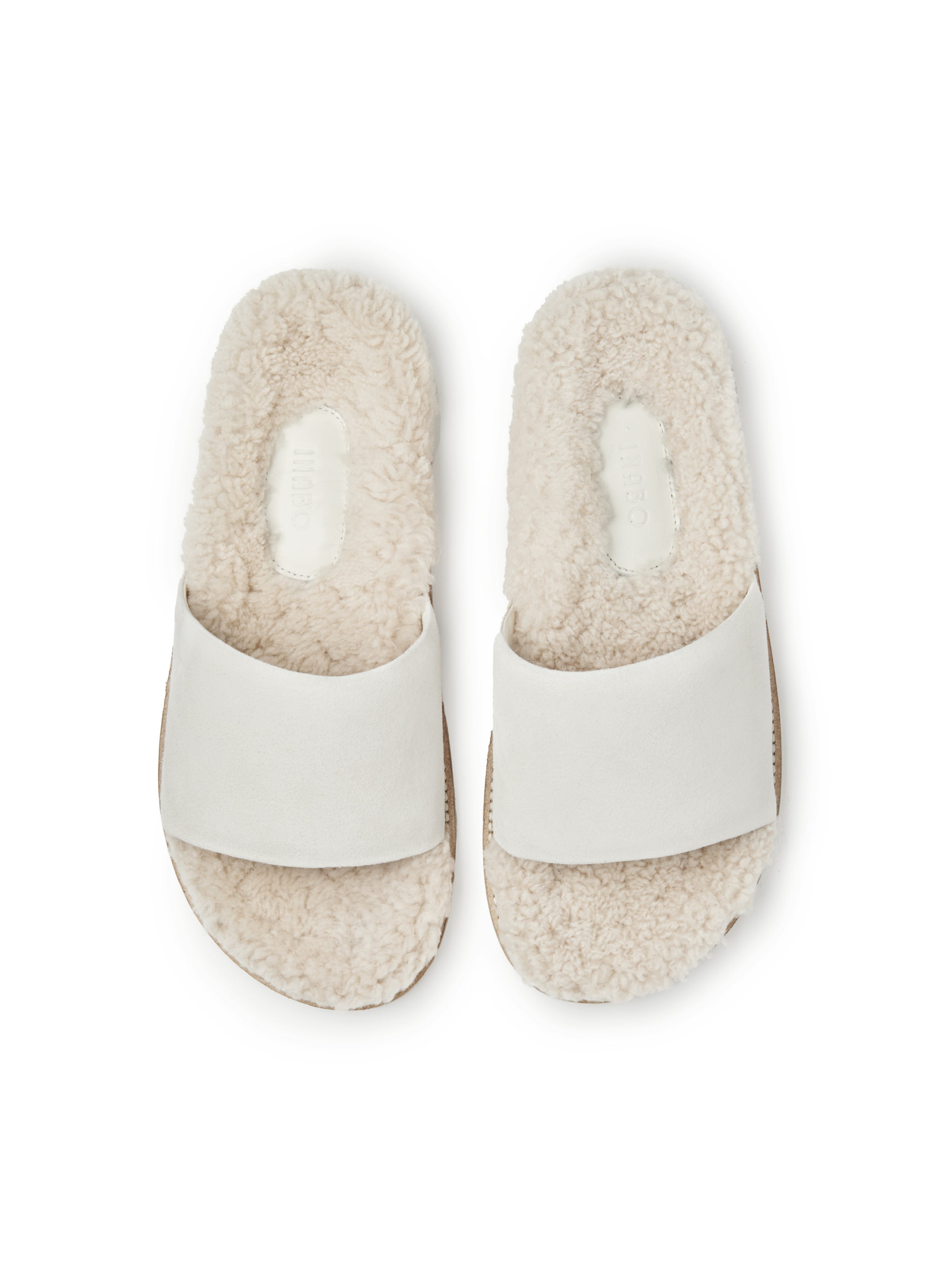 Women's pair of white slippers with shearling lining on a white background