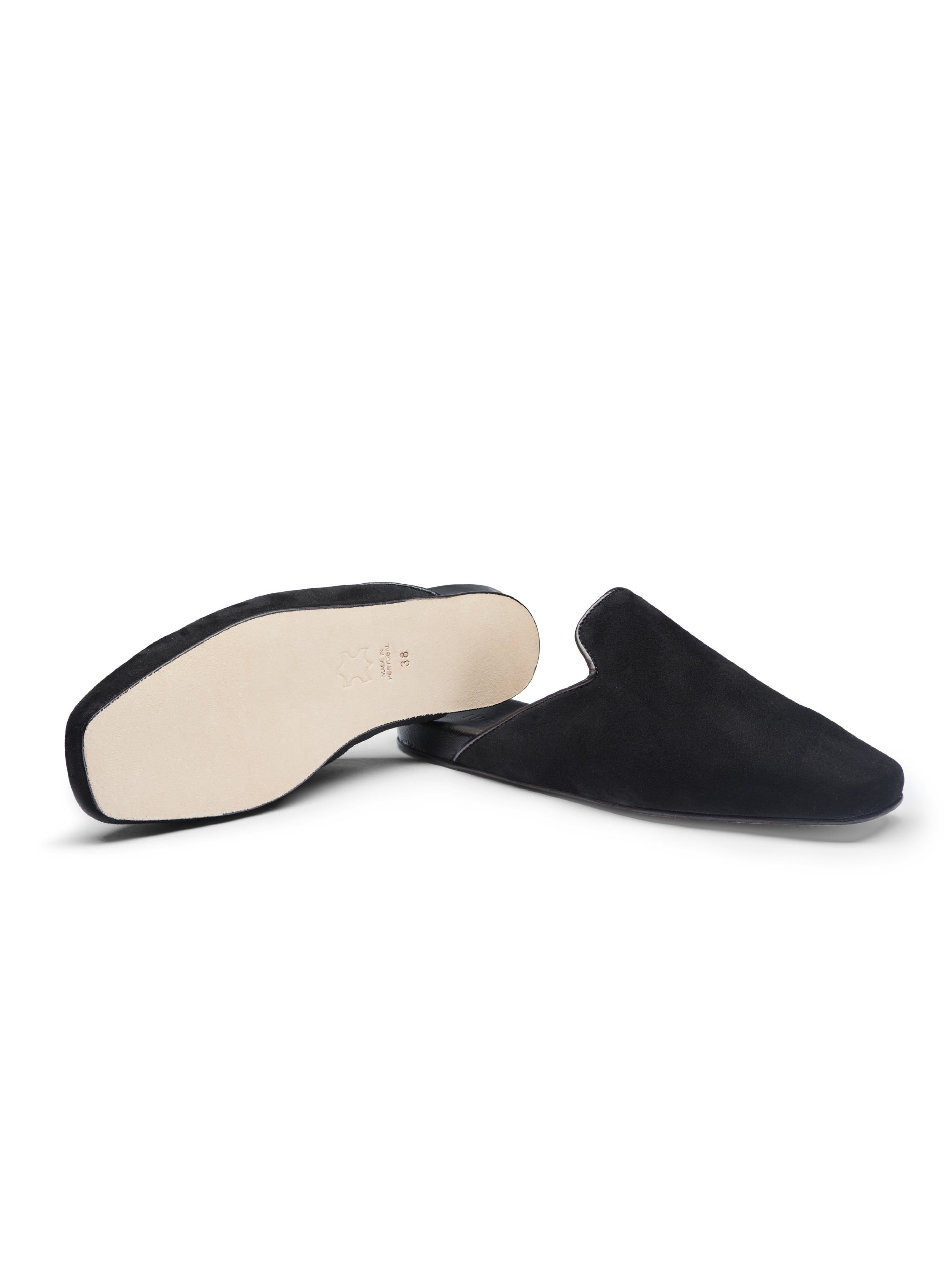 Women's pair of black suede slippers with leather outsole on a white background