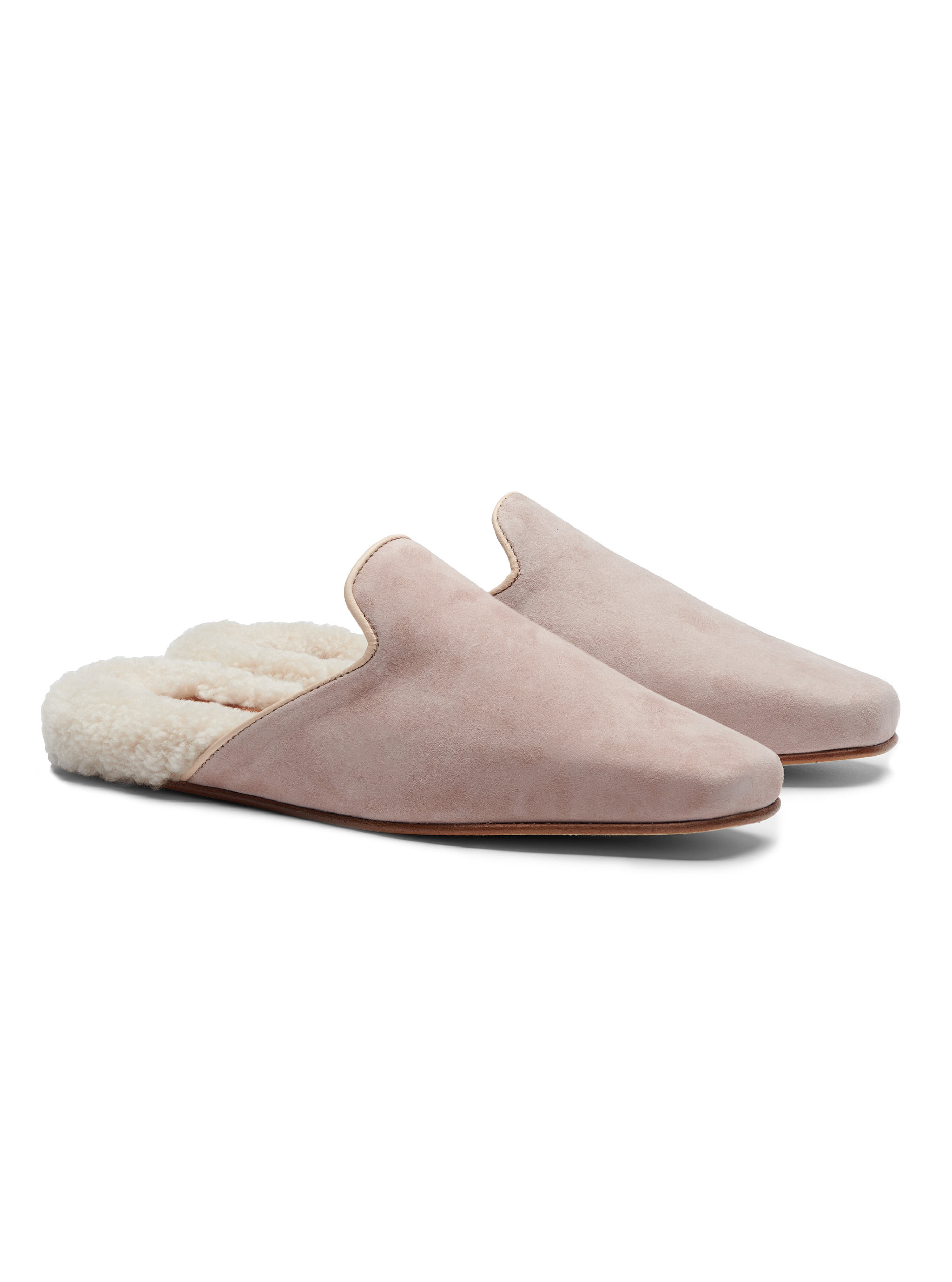 Women's pair of pink suede slippers with shearling lining on a white background