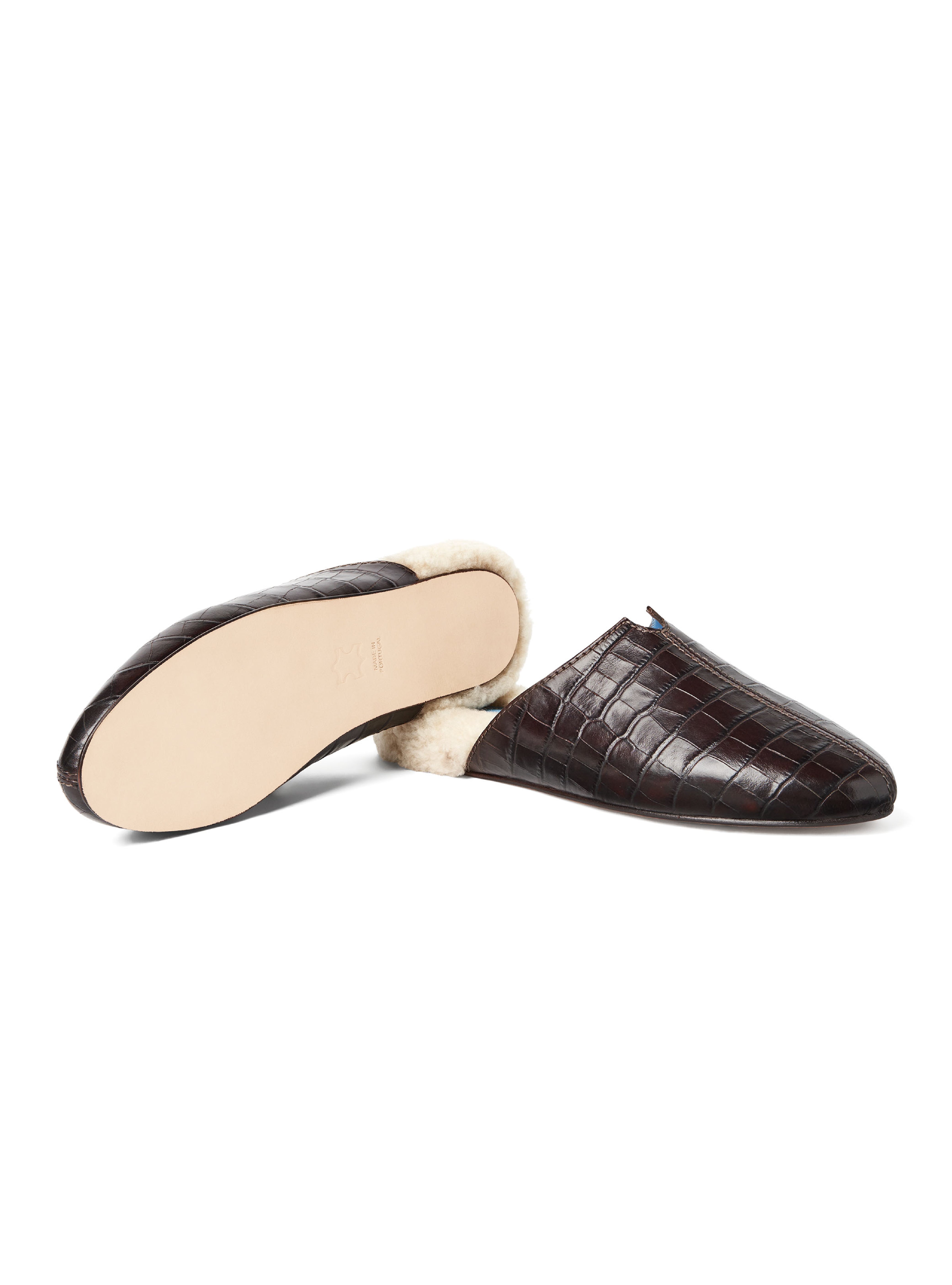 Women's pair of croc-embossed dark brown leather with fur lining and leather outsole on a white background.