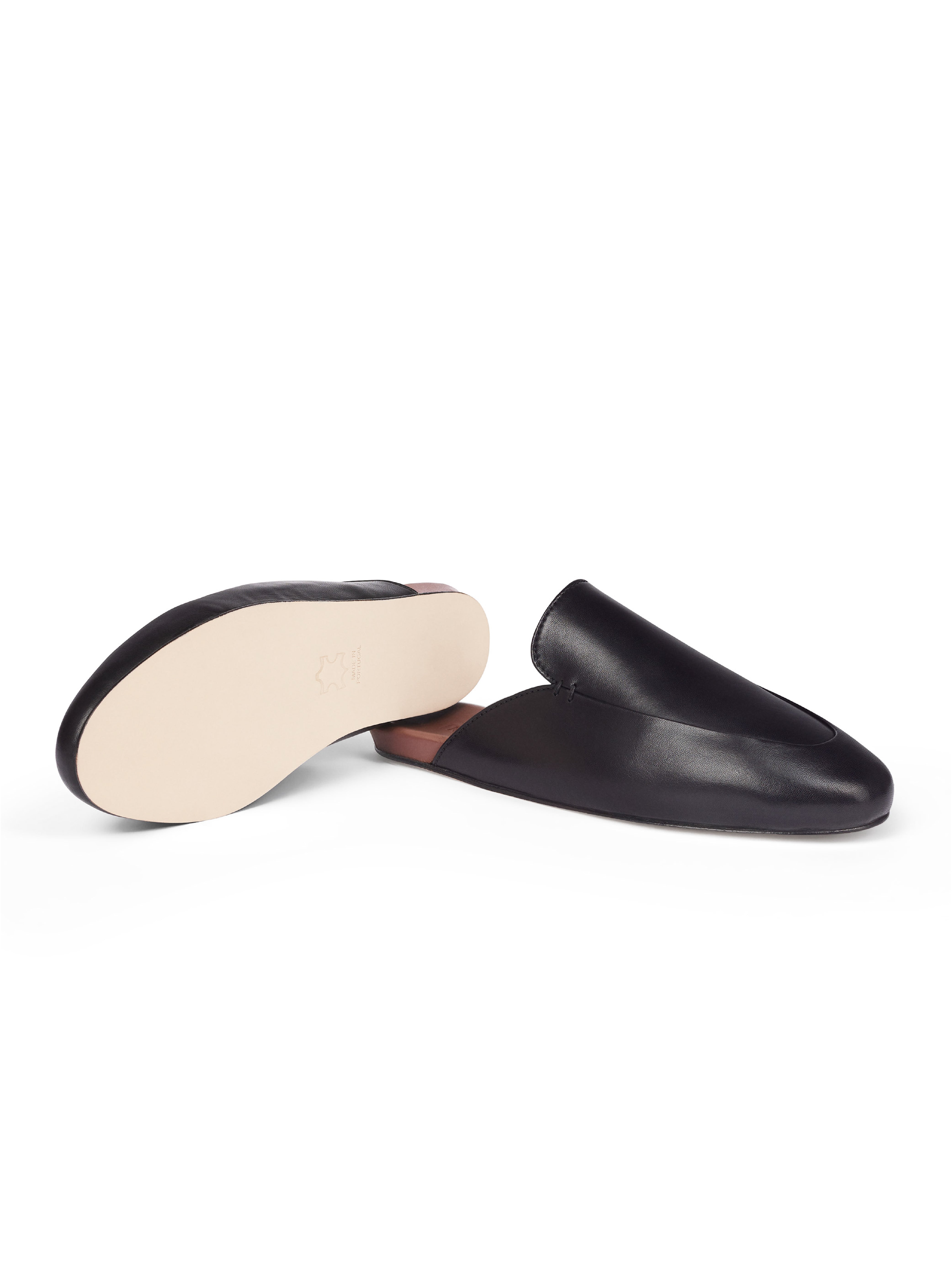 Women's pair of black leather slip-in loafers with leather outsole on a white background.