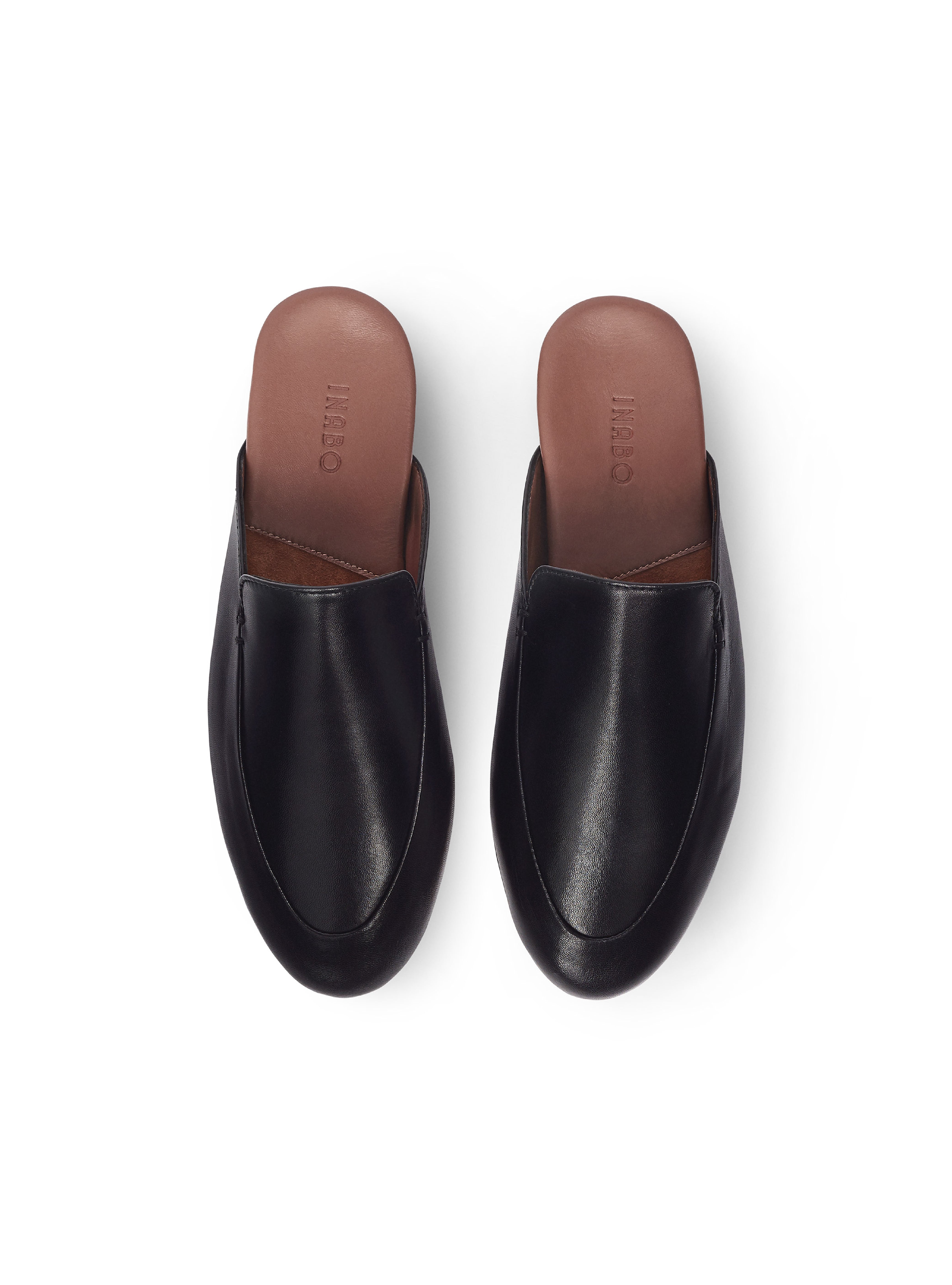 Women's pair of black leather mules with brown soles on a white background